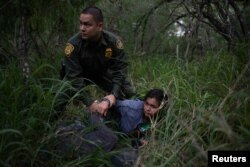A border patrol agent apprehends a woman and a man after they were caught illegally crossing into the U.S. border from Mexico near McAllen, Texas, U.S., May 2, 2018.