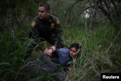 A border patrol agent apprehends a woman and a man after they were caught illegally crossing into the U.S. border from Mexico near McAllen, Texas, U.S., May 2, 2018.