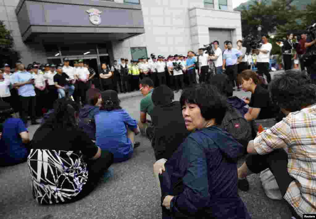 Family members of victims onboard sunken ferry Sewol sit in front of a building in which crew members are detained, after attending a hearing at the local court in Gwangju, South Korea, June 10, 2014.