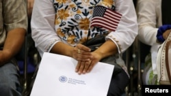 An attendee holds her new country's flag and her naturalization papers as she is sworn in during a U.S. citizenship ceremony in Los Angeles, U.S., July 18, 2017.