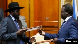 FILE - South Sudan's rebel leader Riek Machar (R) and South Sudan's President Salva Kiir (L) exchange signed peace agreement documents in Addis Ababa, Ethiopia, May 9, 2014.
