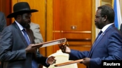 FILE - South Sudan's rebel leader Riek Machar (R) and South Sudan's President Salva Kiir (L) exchange signed peace agreement documents in Addis Ababa, Ethiopia, May 9, 2014.