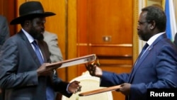 Pemimpin pemberontak Sudan Selatan Riek Machar (kanan) dan Presiden Sudan Selatan Salva Kiir bertukan dokumen perjanjian perdamaian di Addis Ababa, Ethiopia (9/5). 