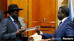 FILE - South Sudan's rebel leader Riek Machar (R) and South Sudan's President Salva Kiir (L) exchange signed peace agreement documents in Addis Ababa, Ethiopia, May 9, 2014.