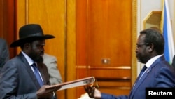 South Sudan President Salva Kiir (L) and opposition leader Riek Machar exchange an agreement signed on May 9 in Addis Ababa, recommitting to a ceasefire deal signed in January but repeatedly violated.