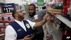 FILE - A Walmart employee, left, is coached by a trainer to use an inventory app at a Walmart store in North Bergen, New Jersey, Nov. 9, 2017.