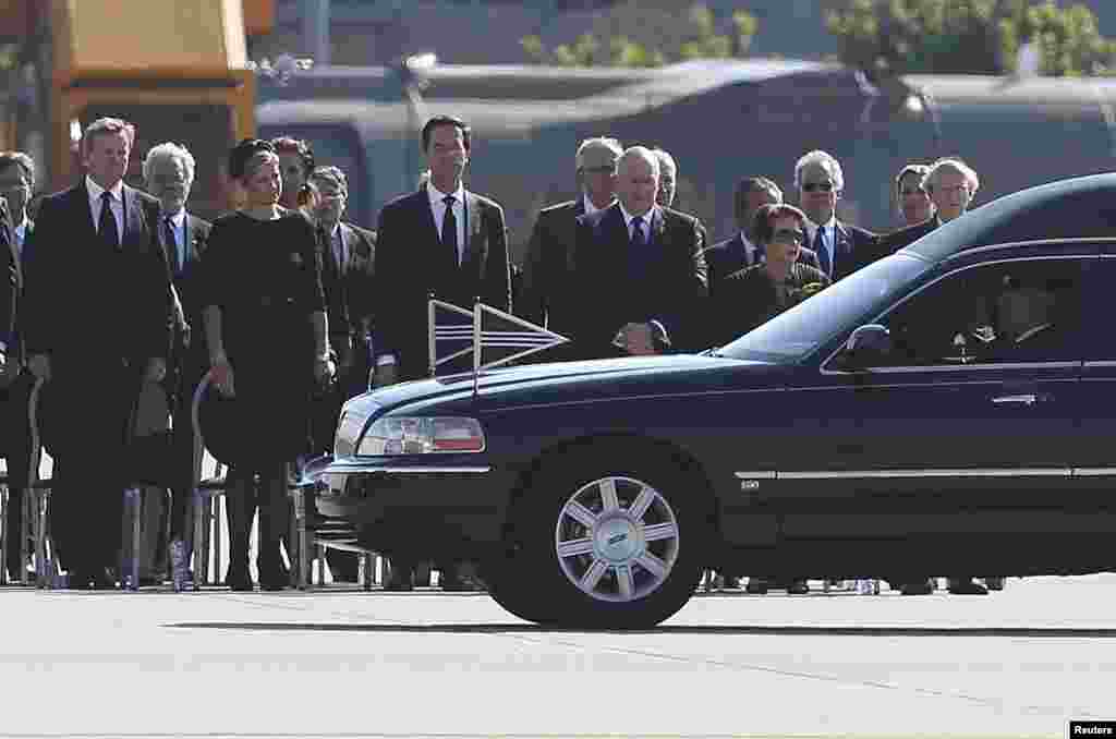 King Willem Alexander, Queen Maxima of the Netherlands, Dutch Prime Minister Mark Rutte and officials look at the convoy of hearses with the remains of the victims of Malaysia Airlines MH17 as it leaves Eindhoven airport to a military base in Hilversum, J