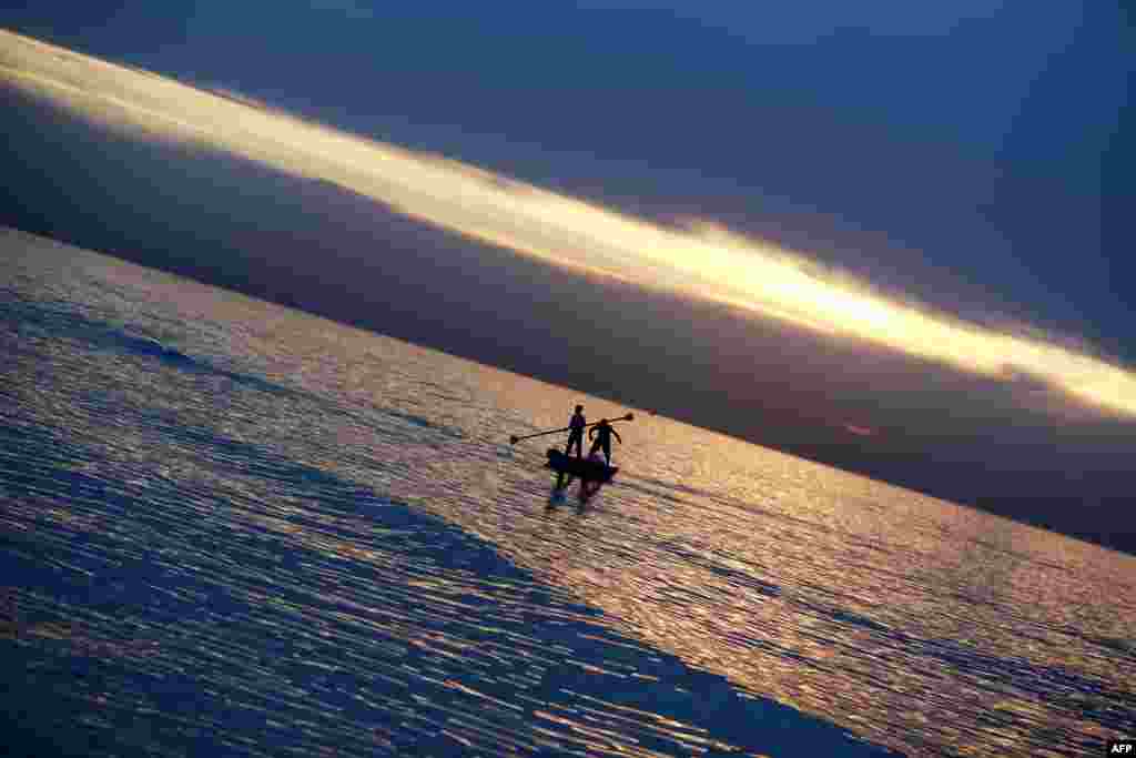 Palestinian youths fish on a small boat at sunset in Gaza City.