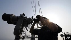 A crew member looks through binoculars on the aircraft carrier USS George Washington during a joint Navy exercise with South Korea in the Yellow Sea, 30 Nov 2010