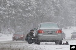 A motorist puts on snow chains near Echo Summit, California, Jan. 3, 2017.