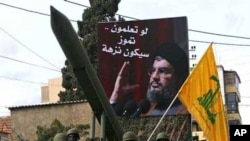 Lebanese Hezbollah fighters stand next to a mock rocket under a poster of Hezbollah's leader Sheik Hassan Nasrallah. (AP Photo/Mohammed Zaatari)