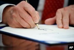 President Donald Trump signs an executive order, Feb. 28, 2017, in the Oval Office of the White House in Washington.