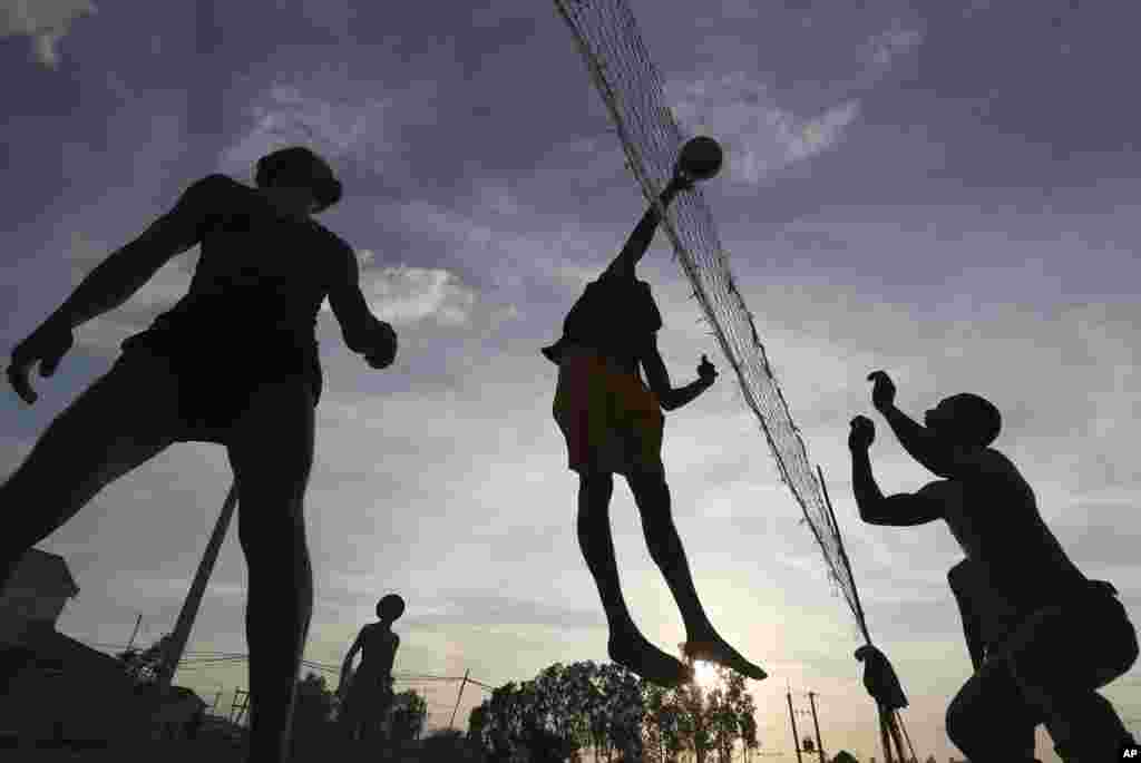 Local construction workers are silhouetted as they play volleyball after work near a construction site at Prey Mou village outside Phnom Penh, Cambodia.