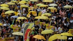 Protesters carry yellow umbrellas during a rally in a downtown street to support for a veto of the government’s electoral reform package in Hong Kong, June 14, 2015.