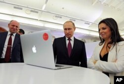 FILE - Russian President Vladimir Putin and Editor-in-chief of RT (formerly Russia Today) 24-hour English-language TV news channel, Margarita Simonyan, are seen at an exhibit marking RT's 10th anniversary in Moscow, Russia, Dec. 10, 2015.