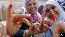 FILE - Egyptian women show their inked fingers after casting their votes at a polling station in Cairo.