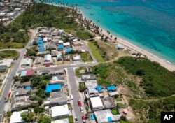 FILE - This June 18, 2018 file photo shows an aerial photo of the Viequez neighborhood, east of San Juan, Puerto Rico, where people were still living in damaged homes, protected by blue plastic tarps, months since Hurricane Maria devastated the island.