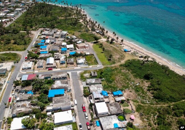 FILE - This June 18, 2018 file photo shows an aerial photo of the Viequez neighborhood, east of San Juan, Puerto Rico, where people were still living in damaged homes, protected by blue plastic tarps, months since Hurricane Maria devastated the island.