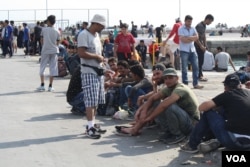 As the passengers loaded, those who could not get a ticket wait on the streets, hoping to board in the coming days, Sept. 12, 2015. (Credit: Heather Murdock/VOA)