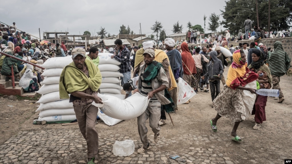 Men carry a sack of wheat during a food distribution by the World Food Programme (WFP) for internally displaced people (IDP) in Debark, 90 kilometers of the city of Gondar, Ethiopia, Sept. 15, 2021.