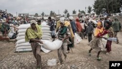 Men carry a sack of wheat during a food distribution by the World Food Programme (WFP) for internally displaced people (IDP) in Debark, 90 kilometers of the city of Gondar, Ethiopia, Sept. 15, 2021.