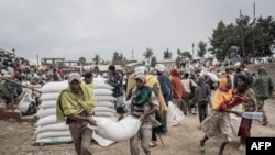 Men carry a sack of wheat during a food distribution by the World Food Programme (WFP) for internally displaced people (IDP) in Debark, 90 kilometers of the city of Gondar, Ethiopia, Sept. 15, 2021.