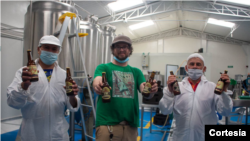 En la planta de la cervecería La Roja, los reintegrados de las FARC, Rubén Darío Jaramillo y Hernando Mayorga (Izq) y el profesor colomboirlandés Wally Broderick (centro) muestran la cerveza que producen en Bogotá. [Foto: Julieta Penagos]