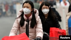 Girls wearing masks ride bicycles amid the heavy haze in Beijing February 22, 2014. 