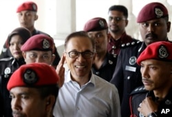 FILE - Deputy Prime Minister and opposition leader Anwar Ibrahim, center, smiles as he arrive at court house in Kuala Lumpur, Malaysia, June 13, 2017.