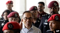 FILE - Deputy Prime Minister and opposition leader Anwar Ibrahim, center, smiles as he arrive at court house in Kuala Lumpur, Malaysia, June 13, 2017.