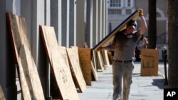 Preston Guiher carries a sheet of plywood as he prepares to board up a Wells Fargo bank in preparation for Hurricane Florence in downtown Charleston, S.C., Tuesday, Sept. 11, 2018. (AP Photo/Mic Smith)