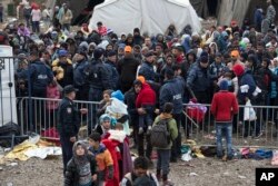 People wait to clear a police line at a registration center for migrants and refugees in Opatovac, Croatia, Oct. 21, 2015.