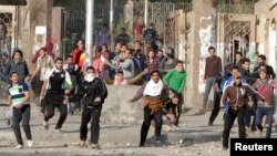 FILE - Students of Al-Azhar University, who are supporters of the Muslim Brotherhood and deposed Egyptian President Mohammed Morsi, clash with riot police and residents at the university campus in Cairo's Nasr City district on January 8, 2014. 