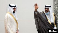 Kuwait's newly appointed Crown Prince Sheikh Meshal al-Ahmad al-Sabah waves before he is sworn in, as parliament Speaker Marzouq al-Ghanim stands next to him, in Kuwait City, Oct. 8, 2020. 