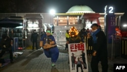 A demonstrator wearing a costume depicting South Korea President Yoon Suk Yeol dances during a sit-in protest calling for Yoon's ouster on the grounds of the National Assembly in Seoul on December 9, 2024.