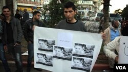 A protester in Ramallah holds a picture of a young Gazan girl and says the violence must stop. He blames Israel but says his leadership must do more. (R.Collard/VOA)