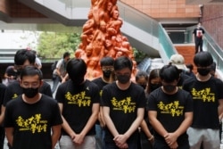 University students observe a minute of silence in front of the Pillar of Shame statue at the University of Hong Kong in Hong Kong, China, June 4, 2021.