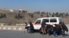 Afghan journalists take cover behind an ambulance near the Intercontinental Hotel during a fight between gunmen and Afghan security forces in Kabul on January 21, 2018.