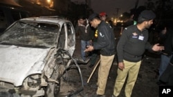 Pakistani police officers check the site of a suicide bombing in Lahore, Pakistan, 25 Jan 2011