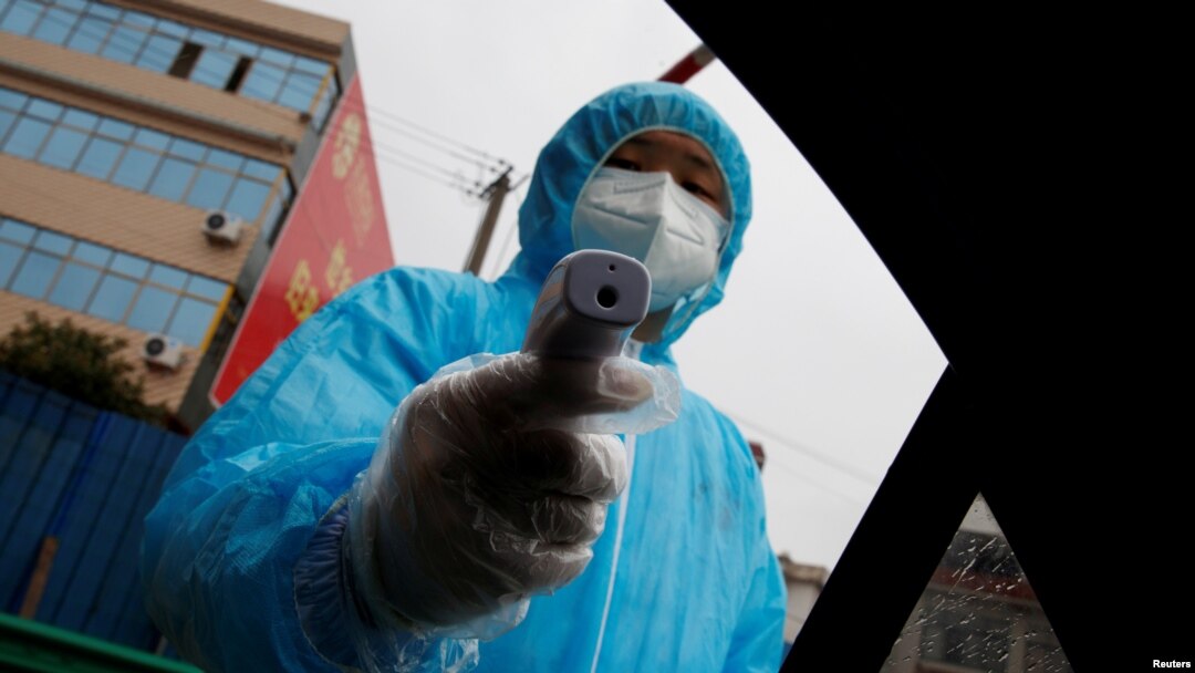 Seorang petugas medis dengan termometer hendak memeriksa suhu tubuh pengendara di pos pemeriksaan di tengah merebaknya wabah virus korona, di Susong County, Provinsi Anhui, China, 6 Februari 2020. (Foto: Reuters)