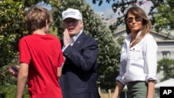 President Donald Trump, center, with first lady Melania Trump and their son Barron Trump, responds to a reporter's question upon arrival at the White House in Washington, from Camp David in Maryland, June 18, 2017.