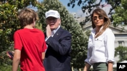 President Donald Trump, center, with first lady Melania Trump and their son Barron Trump, responds to a reporter's question upon arrival at the White House in Washington, from Camp David in Maryland, June 18, 2017.