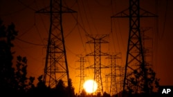 FILE - The sun sets behind high tension power lines on Sept. 23, 2024, in the Porter Ranch section of Los Angeles. The U.S. economy grew at a healthy 2.8% annual rate from July through September, the Commerce Department says.