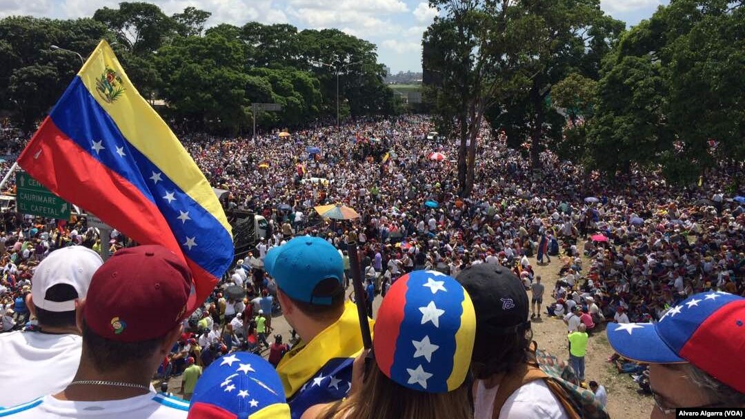 Seorang penentang Presiden Nicolas Maduro melambaikan bendera nasional saat ribuan orang memblokir jalan raya utama di Caracas, Venezuela, hari Sabtu, 20 Mei 2017 (foto: Alvaro Algarra/VOA)