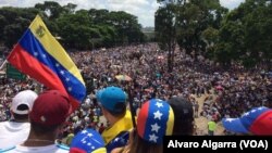 Seorang penentang Presiden Nicolas Maduro melambaikan bendera nasional saat ribuan orang memblokir jalan raya utama di Caracas, Venezuela, hari Sabtu, 20 Mei 2017 (foto: Alvaro Algarra/VOA)