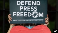 FILE - An employee of the country's largest TV network ABS-CBN, holds a slogan during a rally outside the House of Representatives in Manila, Philippines, July 9, 2020.