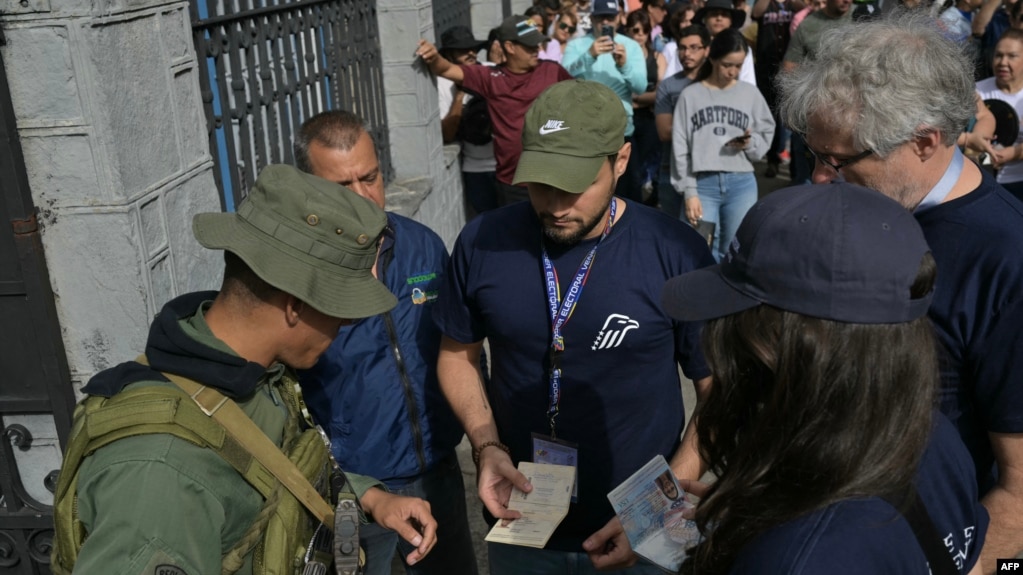 Observadores electorales del Centro Carter muestran sus credenciales a un militar venezolano en la entrada de un centro de votación, el 28 de julio de 2024, en Caracas.