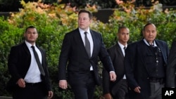 FILE - Tesla CEO Elon Musk, second from left, arrives at U.S. District Court in Los Angeles, Dec. 4, 2019. 