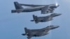 Pesawat B-52H Stratofortress Angkatan Udara A.S., atas, terbang dalam formasi dengan pesawat tempur F-15K Angkatan Udara Korea Selatan di atas laut barat semenanjung Korea selama latihan udara bersama di Korea Selatan, Senin, 6 Maret 2023. (Foto: melalui AP)