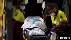 Health care workers wearing protective gear are seen with a patient on a stretcher near the emergency unit at 12 de Octubre hospital, amid the outbreak of the coronavirus disease, in Madrid, Spain, Aug. 14, 2020.